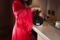 An Asian woman in her red satin nightgown is standing, pouring hot water into a white cup in the middle of the night Royalty Free Stock Photo