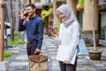 Asian woman in hijab using cell phone near businessman calling Royalty Free Stock Photo