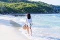 Asian woman holding back straw hat walking on the beach during weekend summer vacation concept ocean waves mountains sandy beach