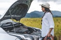 Asian woman holding battery booster cable copper wire for repairing breakdown broken car by connect with red and black line to