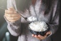 Asian woman holding cooked jasmine rice bowls with spoon. Wearing a gray sweater Royalty Free Stock Photo