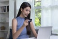 Asian woman holding credit card and using laptop computer. Businesswoman working at home. Online shopping, e-commerce, internet ba Royalty Free Stock Photo