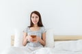 Asian woman holding a cup of tea and sitting on bed Royalty Free Stock Photo