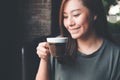 An Asian woman holding and drinking hot coffee with feeling good in vintage cafe