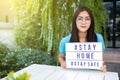 Asian woman holding a lightbox sign with text hashtag #STAY HOME and #STAY SAFE. COVID-19. Stay home save concept