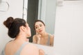 Asian woman holding a mirror, touch and worrying about her face Royalty Free Stock Photo