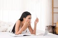 Asian woman holding mockup credit card for shopping online and using laptop in bedroom