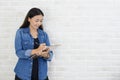 Asian woman holding a notebook and a pen ready to take notes standing near a white wall Royalty Free Stock Photo