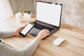Asian woman holding phone and using computer laptop on wooden table Royalty Free Stock Photo
