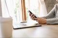 Asian woman holding phone and using computer laptop on wooden table Royalty Free Stock Photo