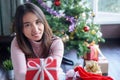 Asian woman holding red gift box on the hands offer to you on christmas tree background