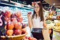 an asian woman holding for shopping an apple in a grocery store, vegan lifestyle concept