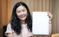 The Asian woman is holding and showing empty white A4 paper portrait - vertical angle on orange brown background Royalty Free Stock Photo