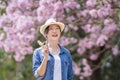 Asian woman holding the sweet hanami dango dessert while walking in the park at cherry blossom tree during spring sakura festival