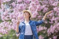 Asian woman holding the sweet hanami dango dessert while walking in the park at cherry blossom tree during spring sakura festival