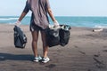 Asian woman cleans plastic from beach, volunteer concept