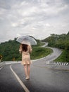 Asian woman holding umbrella on extremely curved road in mountain. Nan, Thailand. sky road on hill. Royalty Free Stock Photo