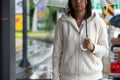 Asian woman holding umbrella while waiting taxi and standing on city sidewalk street in the rainy day