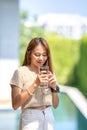 Asian Woman holds a glass of water from drinking at outdoor field with bokeh green banner background Royalty Free Stock Photo