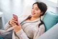 Asian woman, home and smile on couch with smartphone, text and messages with dating app and social media. Above, female