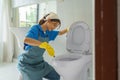 Asian woman housewife scrubbing and cleaning the toilet bowl in the bathroom at home