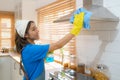 Asian woman housewife using rag and sprayer to clean kitchen hood at home Royalty Free Stock Photo