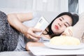 Asian woman indulging in durian fruit while using phone, illustrating the concept of unhealthy lifestyle