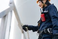 Asian woman Inspection engineer wearing safety harness and safety line working preparing and progress check of a wind turbine with