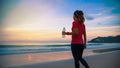 Asian women jogging workout on the beach in the morning. Relax with the sea walk and drinking water from the plastic bottles Royalty Free Stock Photo