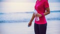 Asian women jogging workout on the beach in the morning. Relax with the sea walk and drinking water from the plastic bottles Royalty Free Stock Photo