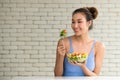 Asian woman in joyful postures with hand holding salad