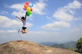 Asian woman jumping on mountain peak rock with colored balloons Royalty Free Stock Photo