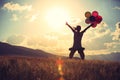 Asian woman jumping on sunset grassland with colored balloons Royalty Free Stock Photo