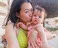 Asian woman kissing her adorable baby girl - beautiful Korean loving mother holding her little daughter hugging her tight and Royalty Free Stock Photo