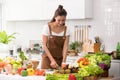 Asian woman in a kitchen cutting vegetables and preparing healthy meal