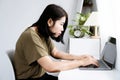 Asian woman with Kyphosis: side view of laptop Work with hunched back, forward head posture, and spinal curvature
