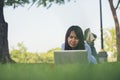 Asian woman lay down green garden park using laptop working outdoor home office. Happiness Woman smile working Freelance on laptop Royalty Free Stock Photo