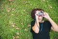 Asian woman laying on the green grass chilly and shoot a photo with her camera.