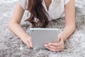 Asian woman lied on gray carpet textured background to use tablet in her house in modern lifestyle concept Royalty Free Stock Photo