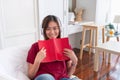 Asian woman listening music on headphone and reading book with relax pose at couch in living room at home.leisure lifestyle Royalty Free Stock Photo