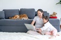 Asian woman and little girl enjoy together in living room by using laptop and sit on the floor while their shiba dog lie on sofa Royalty Free Stock Photo