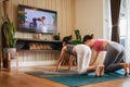 Asian woman and Little girl practicing yoga from yoga online course via smart TV at home. Healthy lifestyle - technology at home. Royalty Free Stock Photo