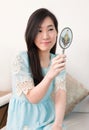 Asian woman looking in classical vintage silver mirror