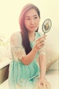 Asian woman looking in classical vintage silver mirror