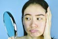 Asian woman looking at her facial problem in the mirror, Female feeling annoy about her reflection appearance show the aging skin. Royalty Free Stock Photo