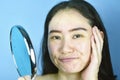 Asian woman looking at herself in the mirror, Female feeling annoy about her reflection appearance show the aging facial. Royalty Free Stock Photo