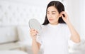 Asian woman looking in mirror at home. Macro japanese female face isolated on white background. Skin care and beauty spa concept.