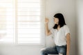 Asian woman looking somthing on window and depression have a headache and feeling absent minded in bedroom