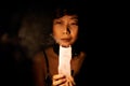 Asian Woman Looks At A Candle Extinguished In Dark. Royalty Free Stock Photo