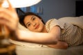 Asian woman lying on the bed turning off the light at the bedside Royalty Free Stock Photo